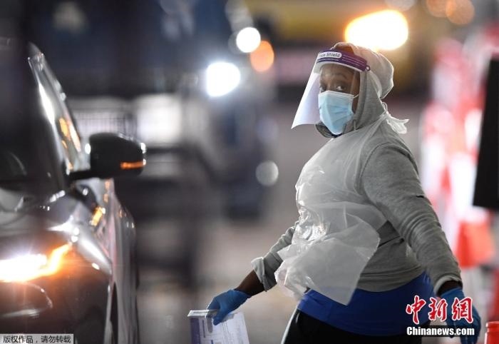 當?shù)貢r間12月18日，英國政府公布的數(shù)據(jù)顯示，當天英國新增奧密克戎毒株感染病例10059例。鑒于奧密克戎毒株感染病例激增，住院人數(shù)不斷上升，倫敦市長宣布倫敦進入“重大事故”狀態(tài)。圖為倫敦的一個免下車檢測中心，一名醫(yī)務(wù)工作者正準備對司機進行核酸檢測。