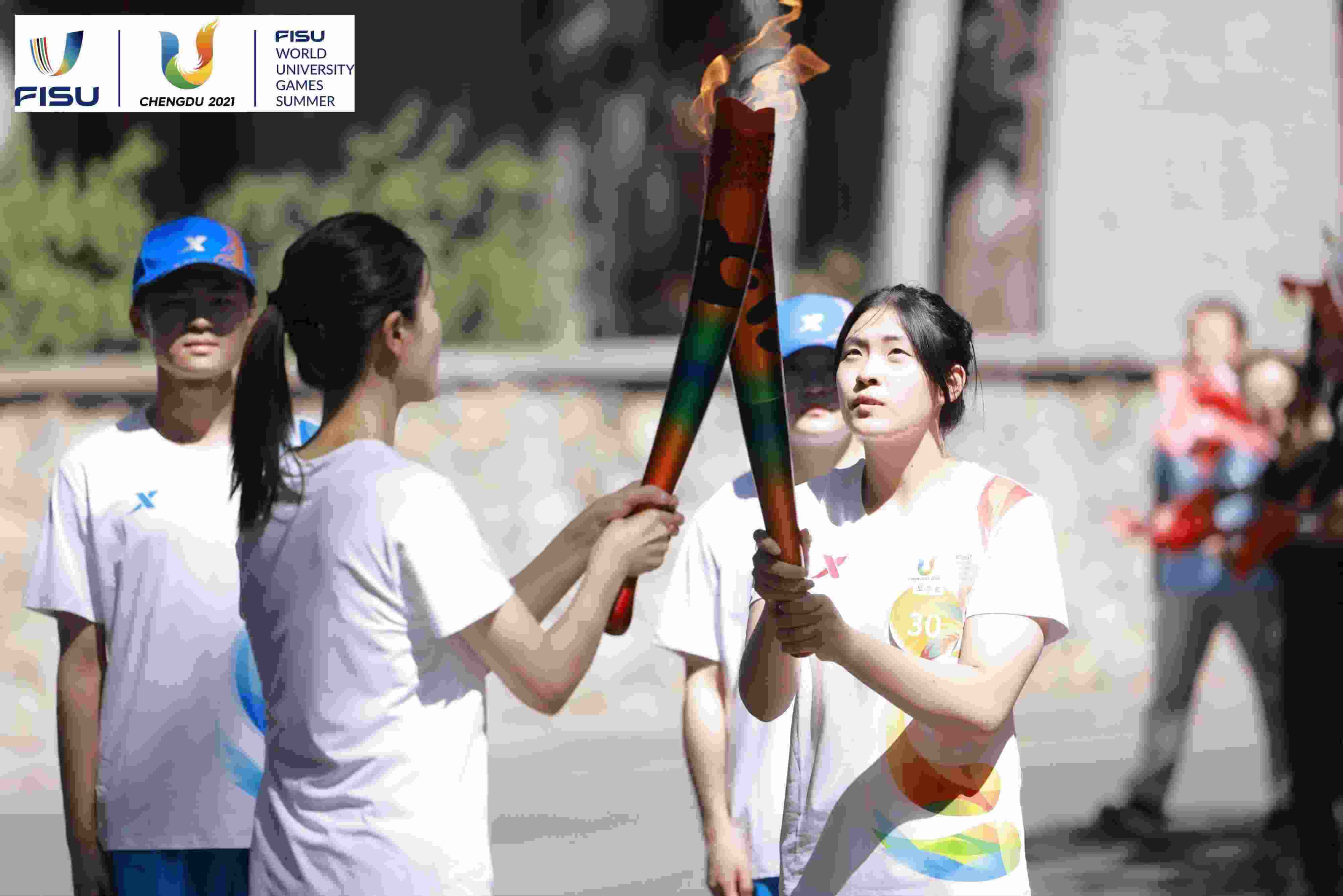 兩名大運會火炬手進行火炬?zhèn)鬟f。 圖片來源：成都大運會執(zhí)委會供圖