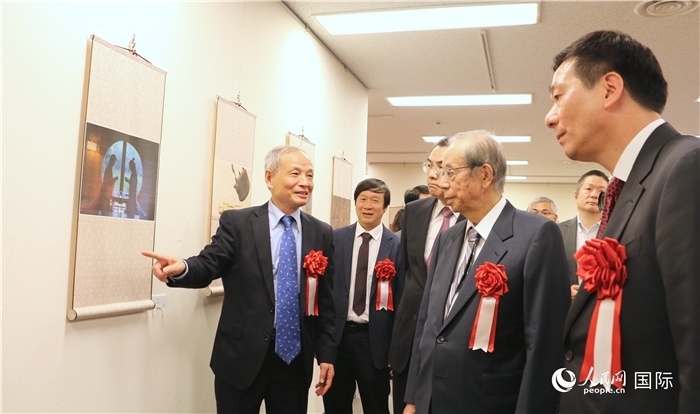 “湖州印象”攝影展主創(chuàng)、世界華人攝影協(xié)會(huì)副會(huì)長(zhǎng)馮學(xué)敏向吳江浩大使、福田康夫前首相等嘉賓介紹展出作品。（人民網(wǎng) 許可攝）