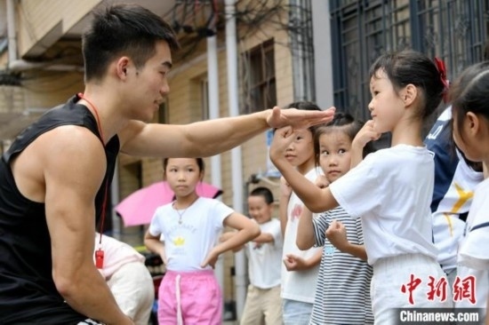 圖為大學(xué)生志愿者在組織孩子們參加體育健身活動(dòng)。廖光福 攝