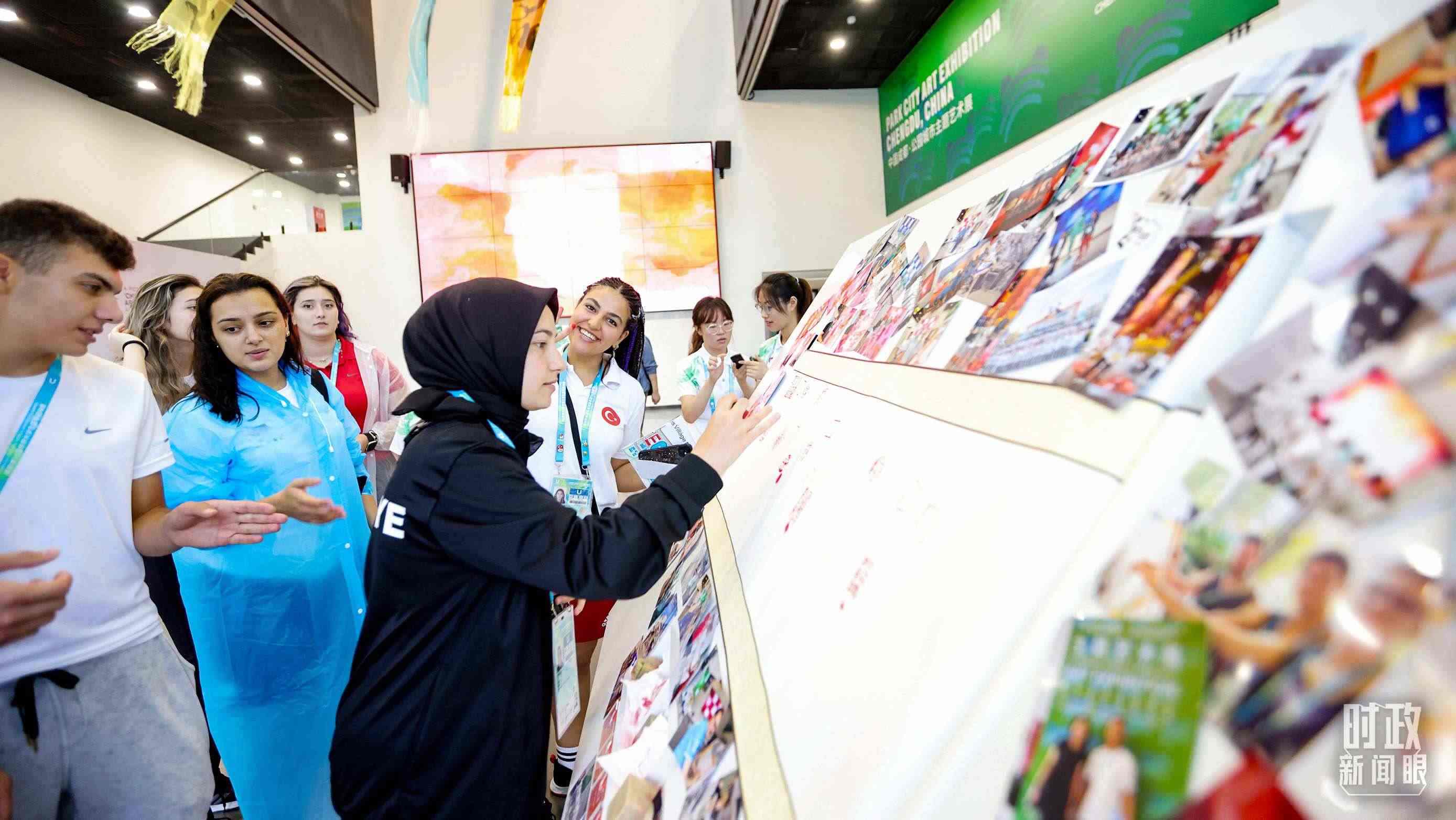 各國青年運(yùn)動(dòng)員正在參觀成都大運(yùn)村內(nèi)的“雪山下的公園城市，煙火里的幸福成都”主題藝術(shù)展。（總臺央視記者魏幫軍拍攝）