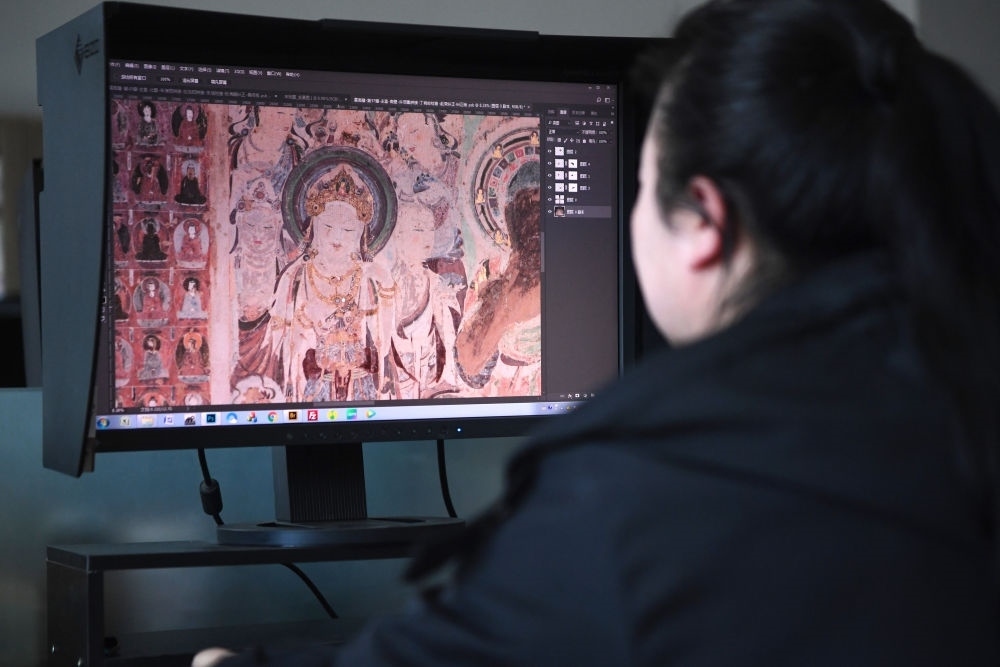 敦煌研究院文物數(shù)字化保護(hù)團(tuán)隊(duì)圖像處理人員年海麗在拼接壁畫圖像（2023年4月25日攝）。數(shù)字化探索為莫高窟的保護(hù)與傳承開辟了全新路徑，數(shù)字技術(shù)讓敦煌文物走出洞窟，跨出國(guó)門，走向“永久保存、永續(xù)利用”。新華社記者 陳斌 攝