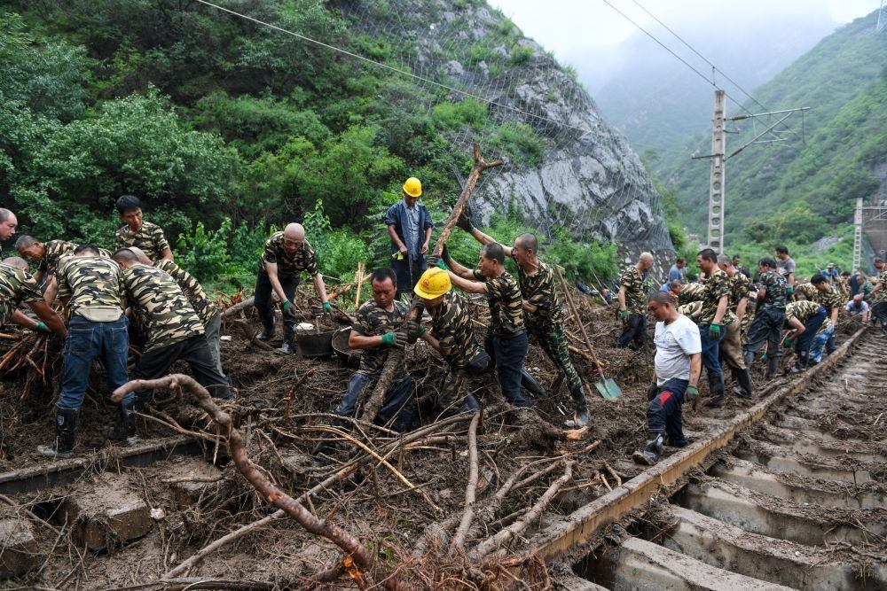 8月1日，在北京市門頭溝區(qū)水峪嘴村附近一段被阻斷的鐵路線上，中鐵六局工作人員在清理軌道上的雜物，全力恢復交通。新華社記者 鞠煥宗 攝