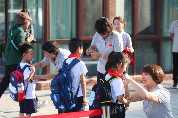 8月30日，雄安史家胡同小學(xué)學(xué)生體驗(yàn)學(xué)校生活。老師為學(xué)生佩戴?；?。