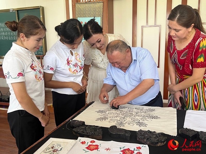 國家級非物質(zhì)文化遺產(chǎn)模戳印花布技藝傳承人吾吉阿西木?吾舒爾展示模戳印花布的制作過程。人民網(wǎng)記者 常雪梅攝
