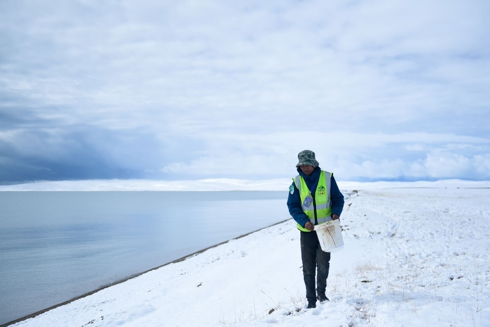 2021年10月20日，在青海省果洛藏族自治州瑪多縣扎陵湖鄉(xiāng)勒那村，三江源國家公園黃河源園區(qū)生態(tài)管護員在扎陵湖邊撿拾垃圾。新華社記者 張龍 攝