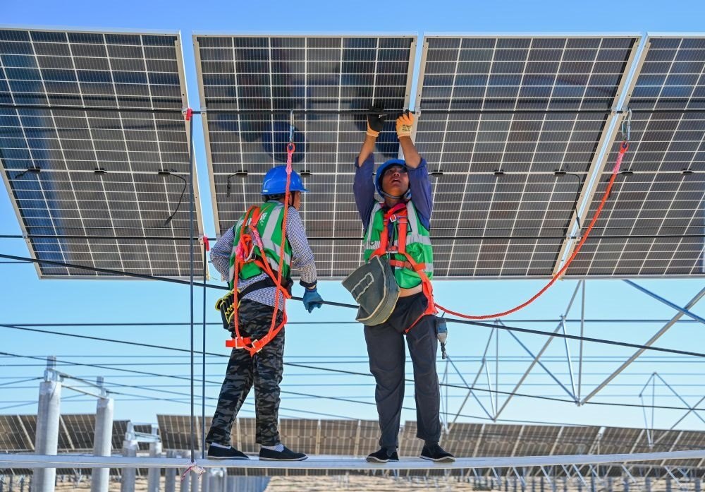 2023年7月22日，工人在位于內(nèi)蒙古杭錦旗庫布其沙漠億利生態(tài)示范區(qū)的蒙西基地庫布其200萬千瓦光伏治沙項目工地安裝光伏板。新華社記者 劉磊 攝