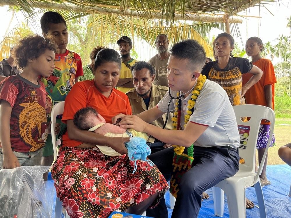 2023年8月5日，在巴布亞新幾內(nèi)亞中央省的一個村莊里，第12批援巴新中國醫(yī)療隊副隊長、新生兒科副主任醫(yī)師劉振球?yàn)楫?dāng)?shù)貗雰郝犜\檢查。新華社發(fā)（第12批援巴新中國醫(yī)療隊供圖）