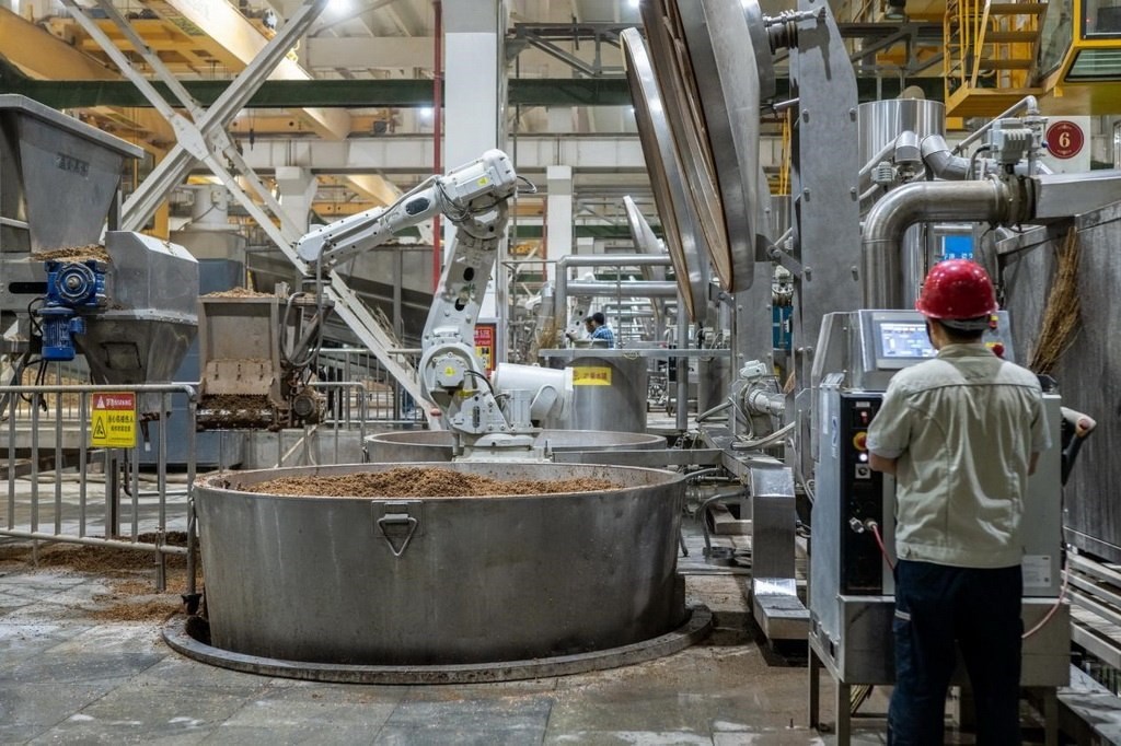 907車間里，機械臂正在撒料裝甑。嚴磊攝