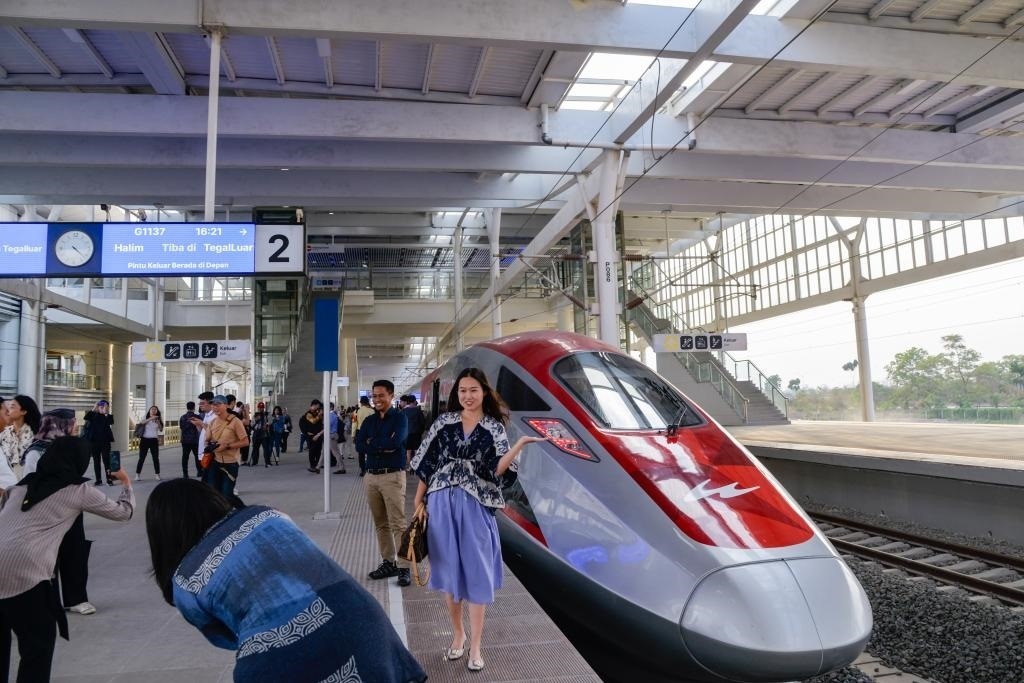 10月17日，在印度尼西亞萬隆德卡魯爾站，乘客在站臺上和雅萬高鐵高速動車組列車合影。