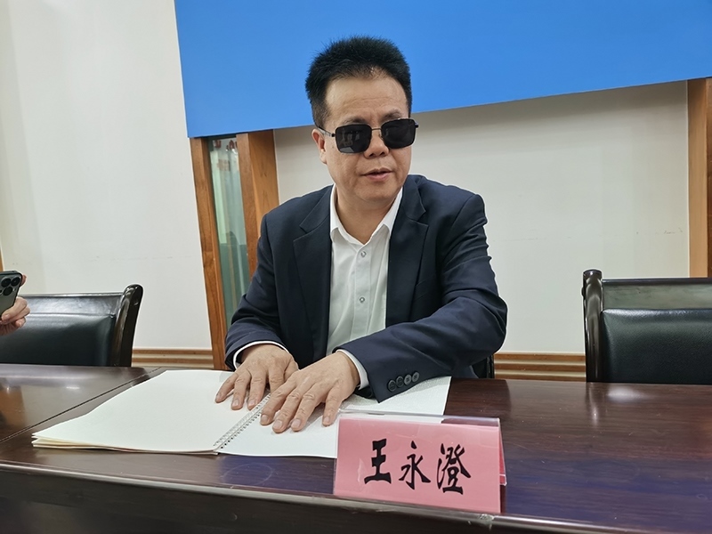 全國人大代表王永澄正在閱讀盲文版代表建議答復(fù)。本報記者 張 璁攝