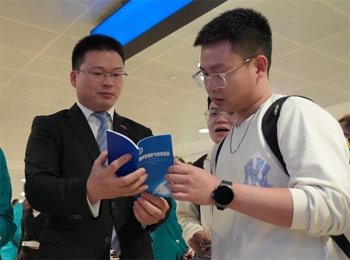 工作人員（左一）在發(fā)放《中國領(lǐng)事保護與協(xié)助指南》。 中國駐迪拜總領(lǐng)事館供圖