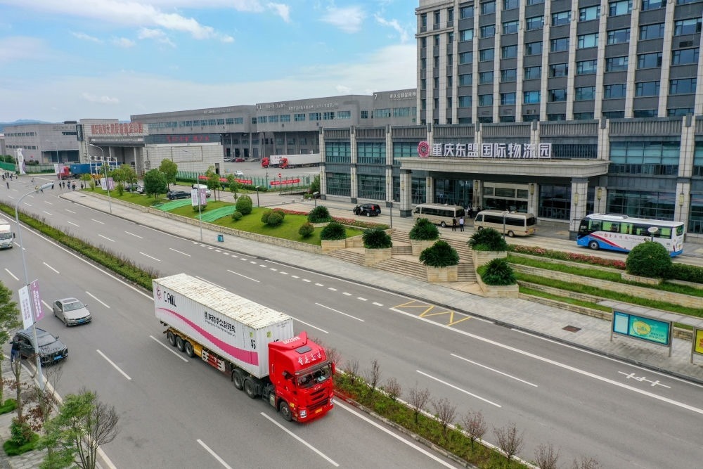 2023年10月11日，滿載筆記本電腦配件、發(fā)電機組件等產(chǎn)品的西部陸海新通道跨境公路班車從重慶南彭公路保稅物流中心駛出，將途經(jīng)廣西憑祥，直達越南（無人機照片）。新華社記者 黃偉 攝