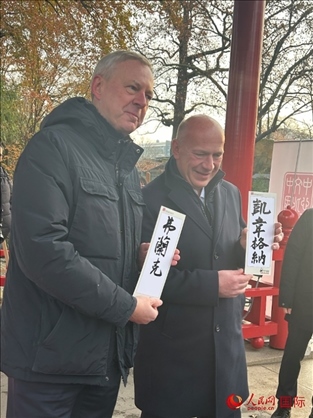 柏林市長韋格納（右）、動物園監(jiān)事會主席布魯克曼（左）手持中國文化中心工作人員現(xiàn)場手書的中文名字。人民網(wǎng)記者 徐馨攝