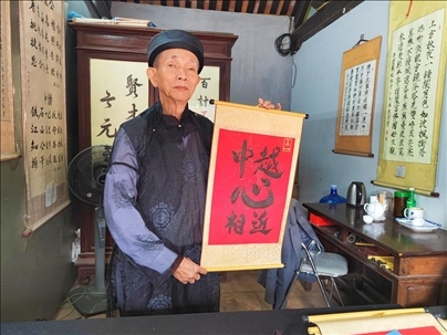 越南首都河內(nèi)文廟內(nèi)，阮明珠展示“中越心相近”書法作品。