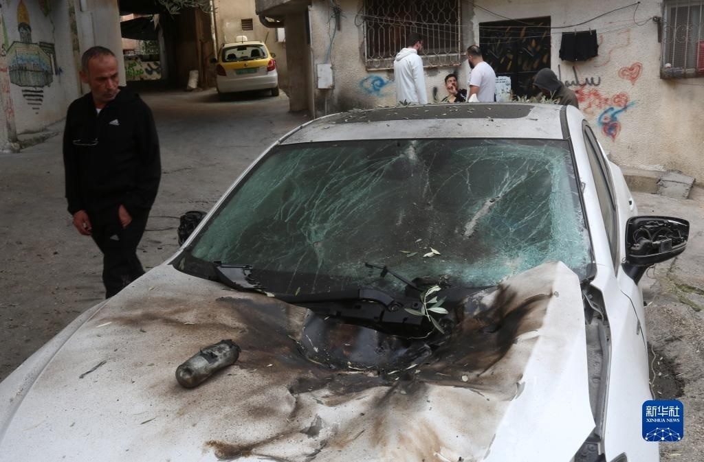 12月17日，在約旦河西岸城市圖勒凱爾姆附近的一處難民營，人們查看在沖突中損毀的車輛。新華社發(fā)（尼達(dá)爾·艾仕塔耶?dāng)z）