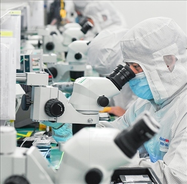 在位于武漢中國光谷的光電器件研發(fā)制造商——武漢光迅科技股份有限公司生產(chǎn)車間內(nèi)，技術(shù)人員在光模塊生產(chǎn)線作業(yè)（2023年4月11日攝）。程敏攝/本刊