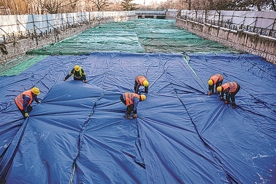 1月3日，房山區(qū)東風(fēng)街道，工人正在修復(fù)的河道內(nèi)給混凝土鋪設(shè)保溫布。