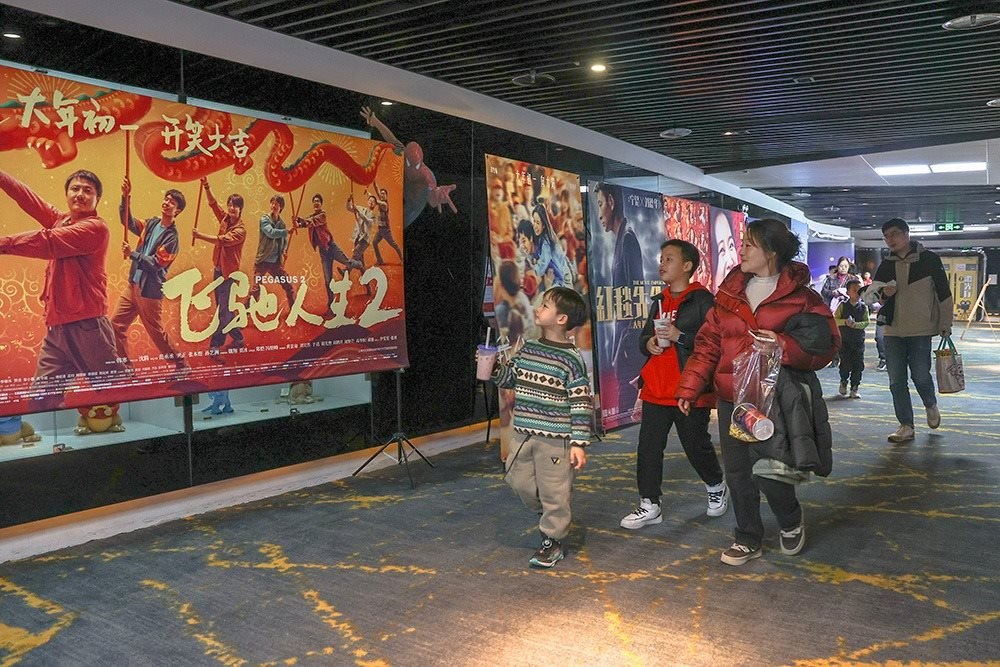 △ 2024年2月16日，在江西贛州一家電影院，觀眾從春節(jié)檔電影的宣傳展板前走過。