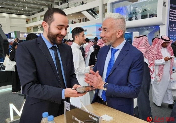 兩名觀眾在榮耀手機展臺前交流。人民網(wǎng)記者 管克江攝