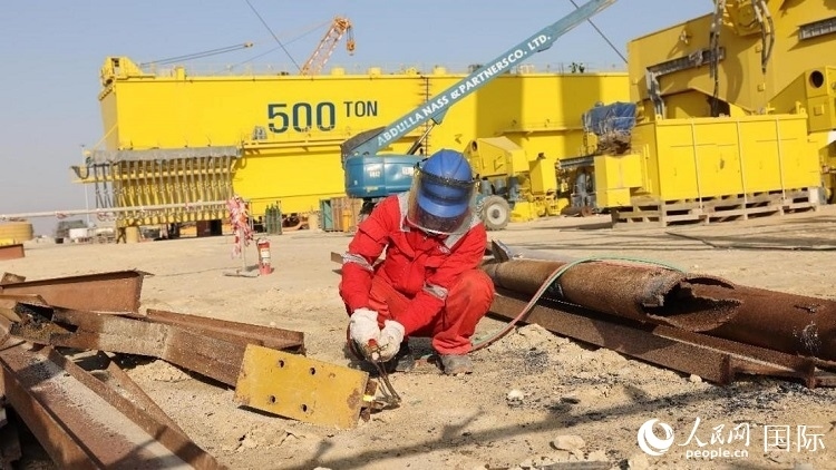 工人正在龍門吊吊裝現(xiàn)場切割金屬件。人民網(wǎng)記者管克江攝