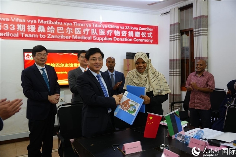 江蘇省蘇北人民醫(yī)院黨委書記束余聲與桑衛(wèi)生部首席秘書哈比巴交換捐贈(zèng)書。中國(guó)援桑醫(yī)療隊(duì)供圖