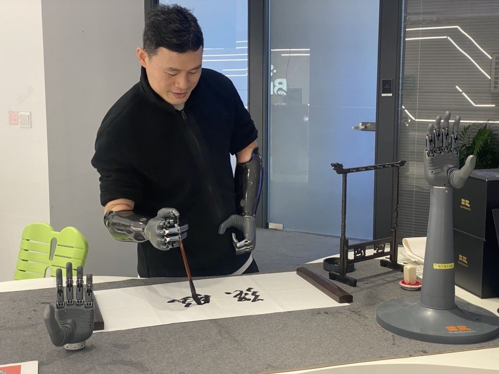 2024年3月29日，在浙江強(qiáng)腦科技有限公司展廳內(nèi)，失去雙手的產(chǎn)品體驗官倪敏成依靠智能仿生手寫毛筆字。新華社記者 魏一駿 攝