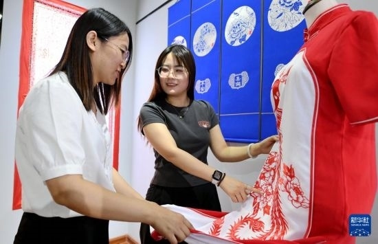 5月31日，在衡水市阜城縣一家剪紙工作室，游客在觀賞帶有剪紙?jiān)氐钠炫邸? width=