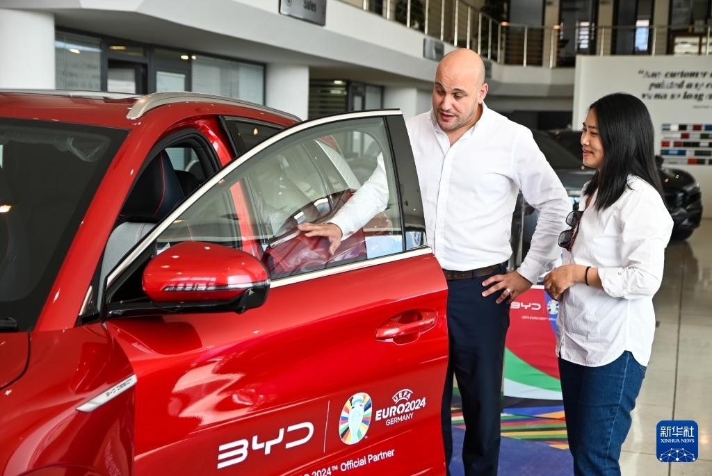 2024年5月29日，在馬耳他比爾基卡拉，馬耳他哈桑-扎米特汽車公司首席執(zhí)行官德古阿拉（左）介紹一輛比亞迪純電動汽車。新華社發(fā)（喬納森·博格 攝）