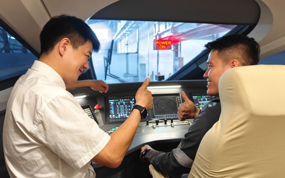 2023年8月25日，在印度尼西亞萬隆的雅萬高鐵德卡魯爾動車所內(nèi)，中國師傅穆振（左）向印尼火車司機塞蒂亞萬講解動車組出庫前的上電作業(yè)。新華社記者 徐欽 攝