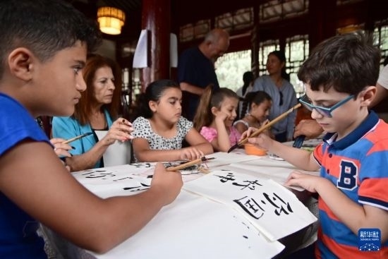 7月4日，在馬耳他桑塔露琪亞市的中國(guó)古典園林“靜園”，人們體驗(yàn)中國(guó)書(shū)法。新華社發(fā)（喬納森·博格 攝）