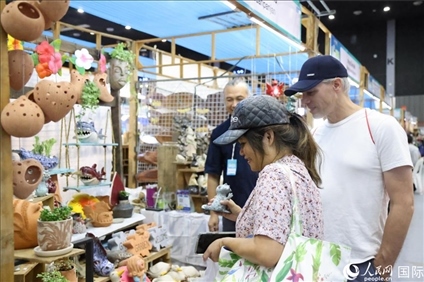 游客在蘭納博覽會特色展位上選購工藝品。人民網(wǎng)記者楊一攝