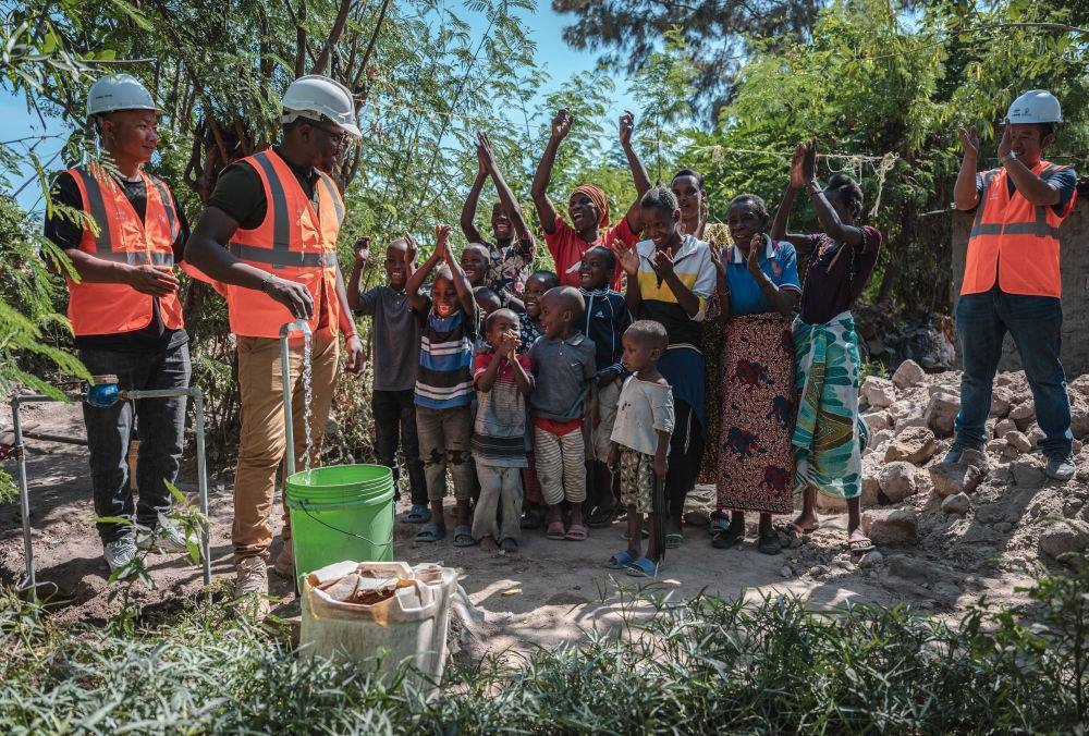 2023年6月13日，在坦桑尼亞姆萬扎省米松圭，工作人員接通水管后贏得當(dāng)?shù)鼐用窆恼茪g呼。新華社記者 王冠森 攝