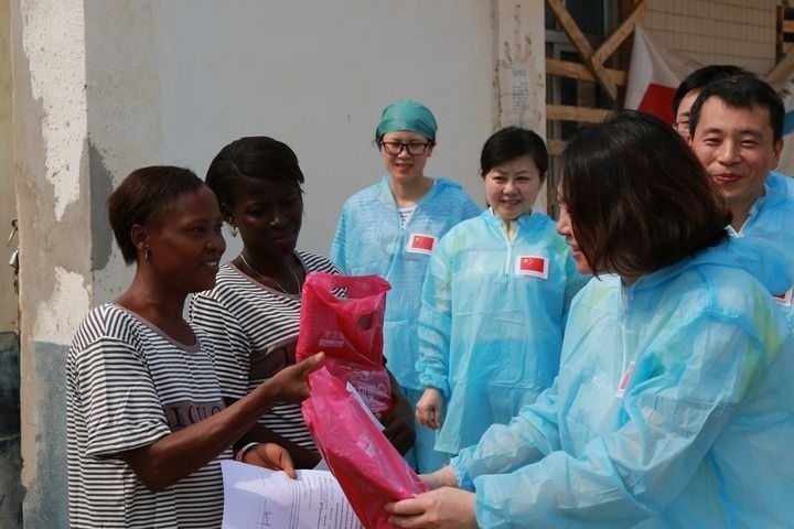 2015年4月4日，在位于塞拉利昂首都弗里敦市郊的中塞友好醫(yī)院埃博拉診療中心，中國第四批援塞醫(yī)療隊副隊長邵蔚（右前）向被治愈的埃博拉出血熱患者贈送禮物。新華社發(fā)（祖榮強 攝）