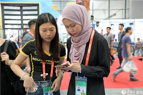 東博會現(xiàn)場，馬來西亞展商在同中方工作人員交談。人民網(wǎng)記者 趙益普攝