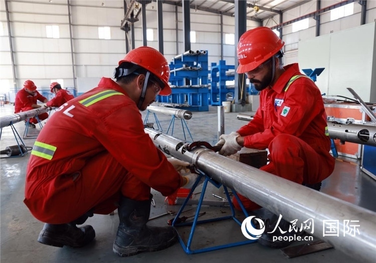 中伊員工共同在檢修鉆井設(shè)備。人民網(wǎng)記者管克江攝