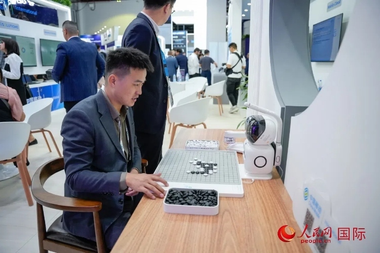 觀眾在中國移動(dòng)國際有限公司展臺體驗(yàn)智慧圍棋機(jī)器人。人民網(wǎng) 塔里克·易卜拉欣攝