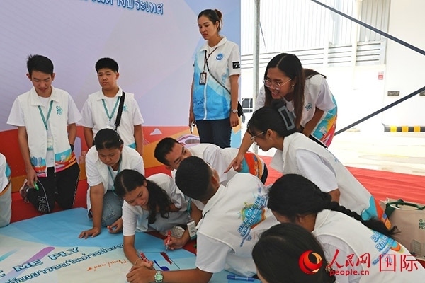 泰國學生在開營儀式展板上繪制圖案。人民網(wǎng)記者 白元琪攝