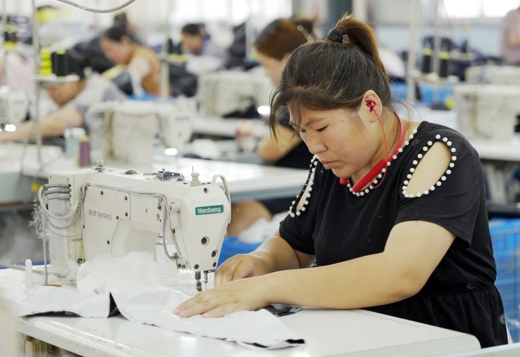 5月20日，村民在李寨村服裝加工廠內(nèi)忙碌。河南省周口市沈丘縣馮營鎮(zhèn)李寨村地處豫東平原。近年來，乘著脫貧攻堅與鄉(xiāng)村振興政策的東風(fēng)，李寨村積極探索產(chǎn)業(yè)發(fā)展模式，通過“龍頭企業(yè)+村集體經(jīng)濟(jì)+農(nóng)戶”的方式，逐漸發(fā)展形成肉牛養(yǎng)殖、設(shè)施農(nóng)業(yè)、服裝加工、康養(yǎng)民宿等產(chǎn)業(yè)，以產(chǎn)業(yè)振興助力鄉(xiāng)村振興。新華社記者 李嘉南 攝