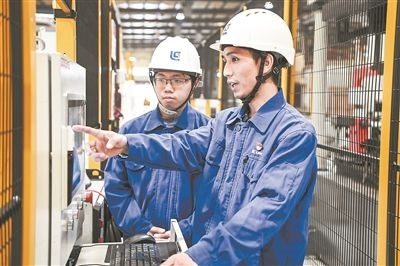 在廣西柳工機(jī)械股份有限公司生產(chǎn)車間內(nèi)，一名高級技師（右）給徒弟講解數(shù)控設(shè)備操作細(xì)節(jié)。新華社記者 曹祎銘攝