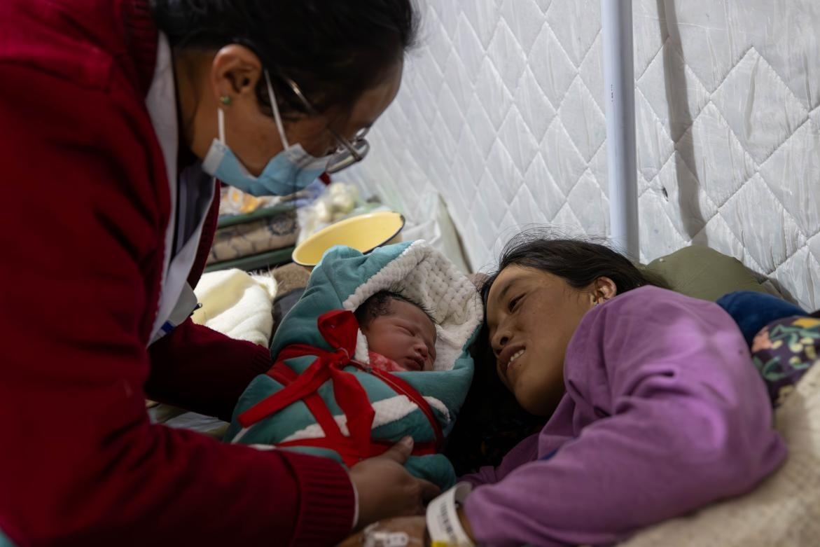 1月10日，定日縣中心醫(yī)院的婦產(chǎn)科醫(yī)生悉心照看一位母親和她懷里的新生兒。人民日報記者張武軍攝