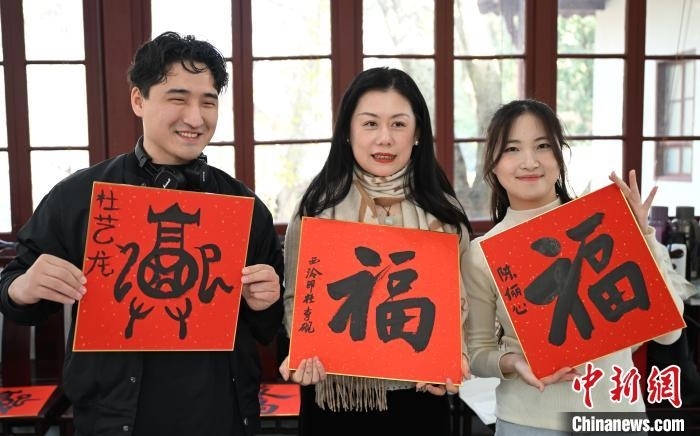 1月20日，外籍留學(xué)生和西泠印社社員李硯(中)展示各自創(chuàng)作的福貼。當(dāng)日，來自巴西、馬來西亞、加納、哈薩克斯坦的外籍留學(xué)生在浙江杭州西泠印社體驗(yàn)福貼、春聯(lián)和篆刻，感受古老的中國傳統(tǒng)文化。中新社記者 王剛 攝