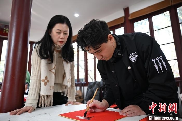 1月20日，外籍留學(xué)生在西泠印社社員李硯指導(dǎo)下寫福。當(dāng)日，來自巴西、馬來西亞、加納、哈薩克斯坦的外籍留學(xué)生在浙江杭州西泠印社體驗(yàn)福貼、春聯(lián)和篆刻，感受古老的中國傳統(tǒng)文化。中新社記者 王剛 攝