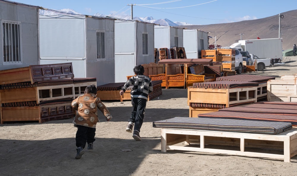 2025年1月13日，在定日縣嘎旦村，兩個(gè)孩子在剛運(yùn)來的兩排藏床間奔跑。新華社記者丁增尼達(dá) 攝