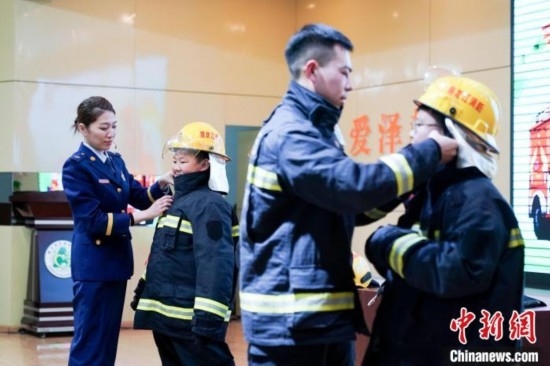 圖為學(xué)生們現(xiàn)場穿戴消防頭盔和戰(zhàn)斗服。中新社記者 趙宇航 攝