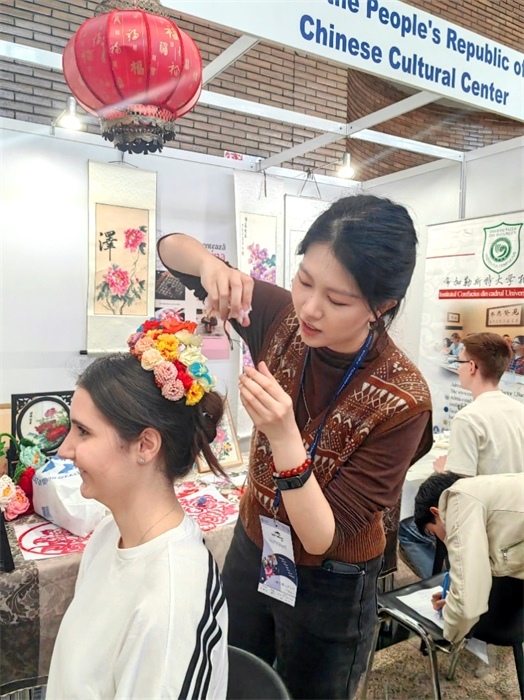 展覽正值羅馬尼亞迎春花節(jié)，國際中文教師志愿者潘婧穎向游客們介紹了國家非物質(zhì)文化遺產(chǎn)——福建泉州的簪花文化。布加勒斯特大學(xué)孔子學(xué)院供圖。