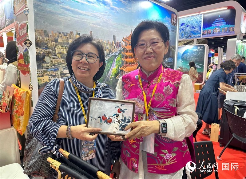 中國“大冶刺繡”傳承人劉小紅（右）參加泰國國際旅游展，向觀眾介紹中國非遺刺繡針法。人民網(wǎng)記者 簡承淵攝