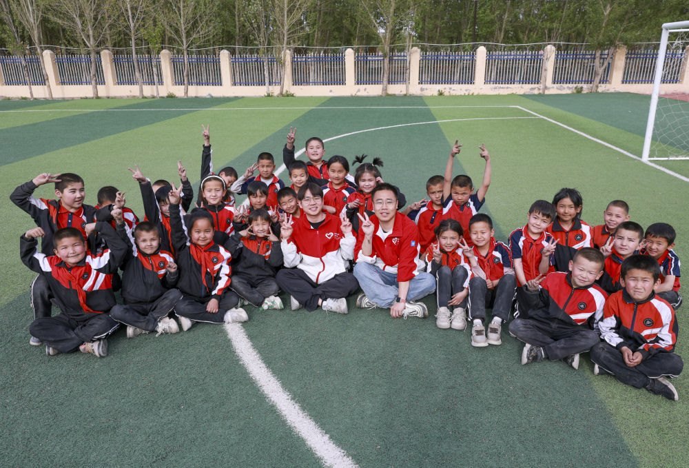 4月23日，在新疆克州阿圖什市哈拉峻鄉(xiāng)謝依特小學(xué)，支教教師王俊文（中左）、李軻凡（中右）和學(xué)生在一起。