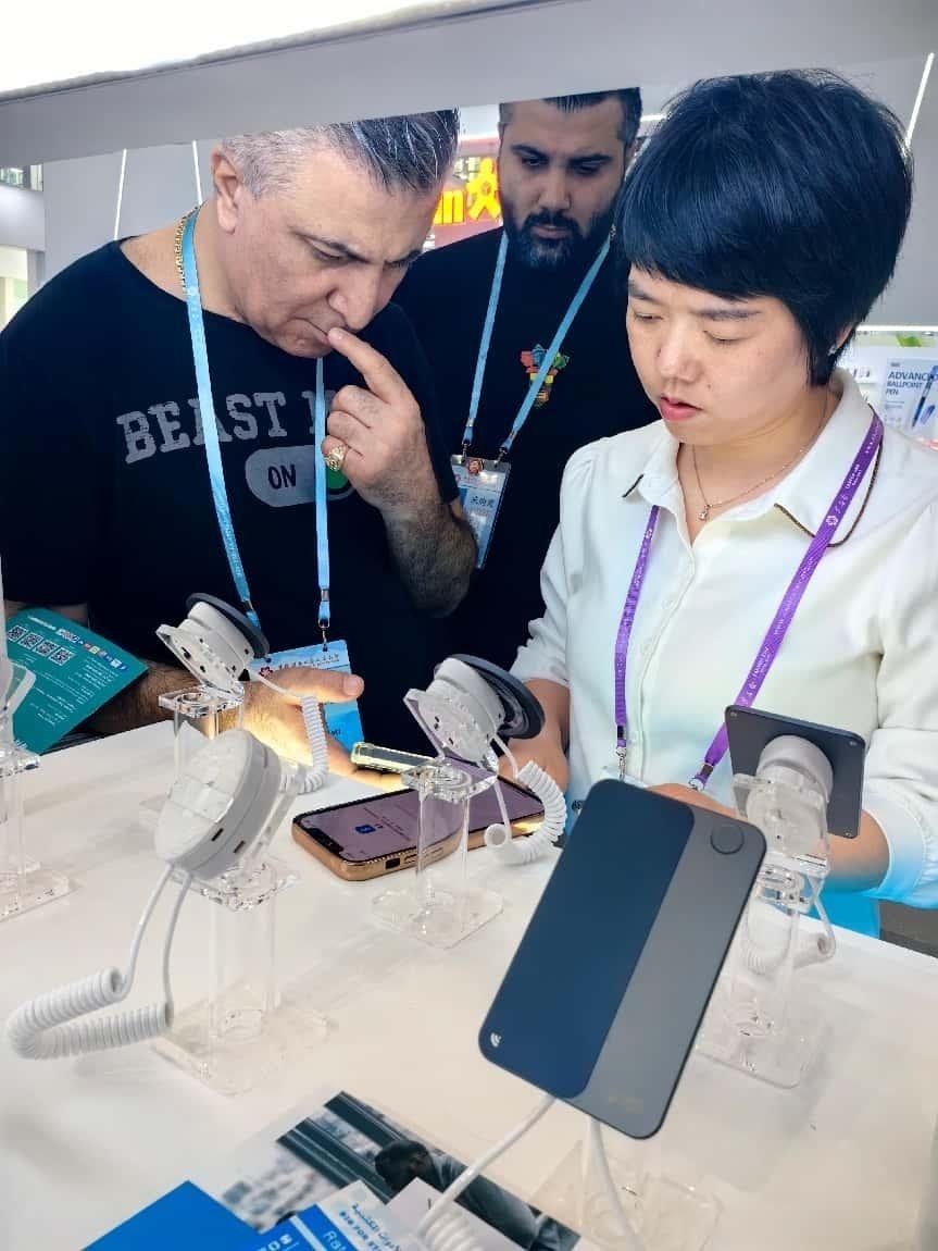 展臺工作人員向外商展示“AI TOP翻譯終端”。圖片來源：受訪者提供