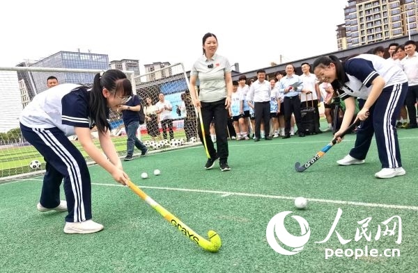 陳朝霞（中）指導(dǎo)學(xué)生體驗曲棍球。 人民網(wǎng)記者 楊磊攝